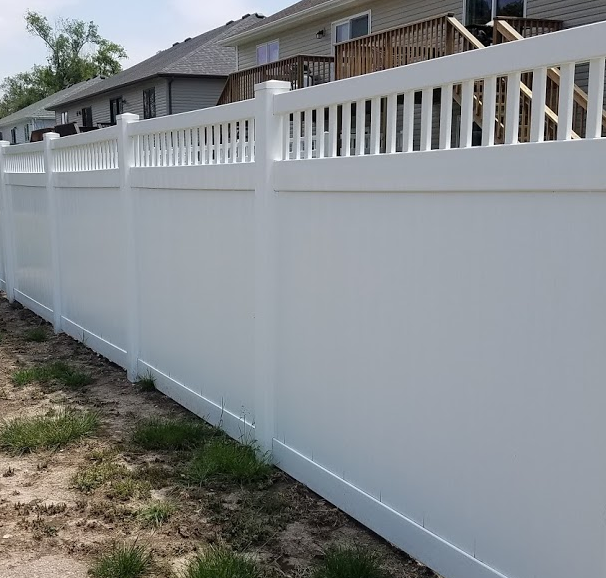 Solid white vinyl fence with vertical picket accents around a residential backyard